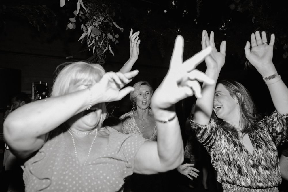 Black and white photo of people dancing with raised hands at a celebration.