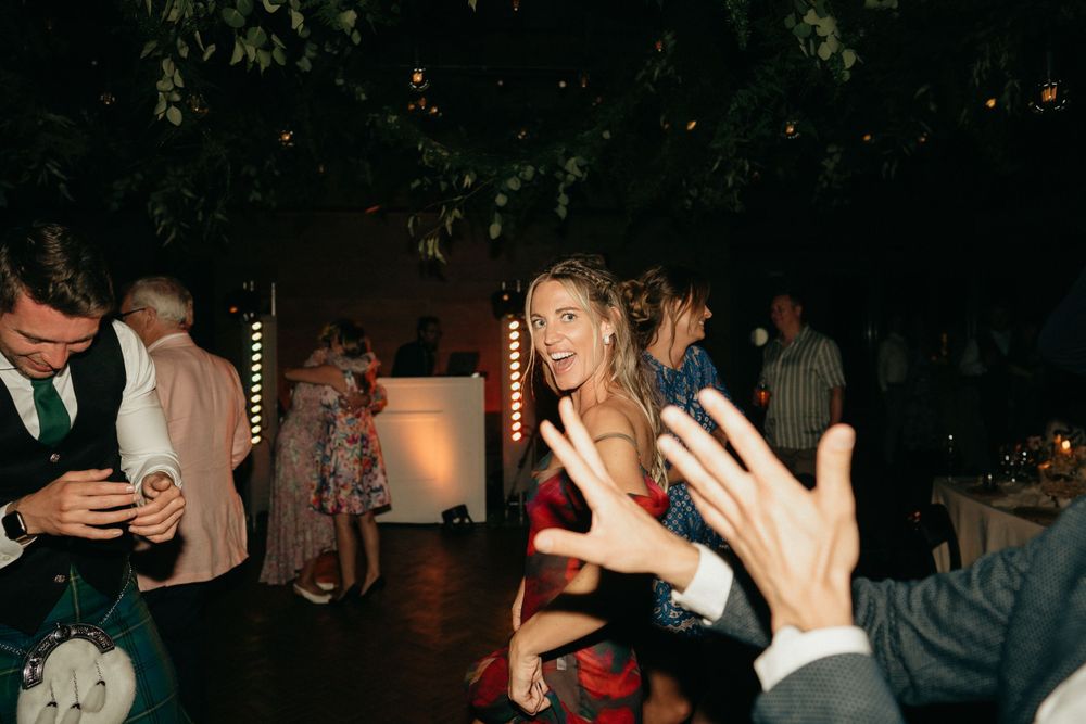 Wedding reception guests dancing and celebrating under atmospheric lighting.