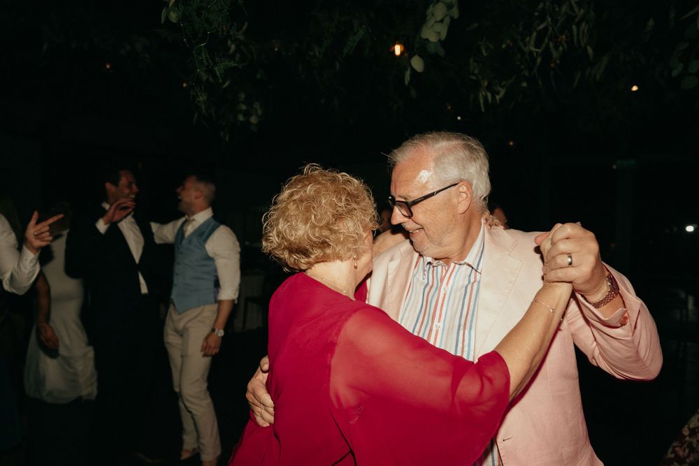Elderly couple shares a tender dance moment at an evening wedding reception.