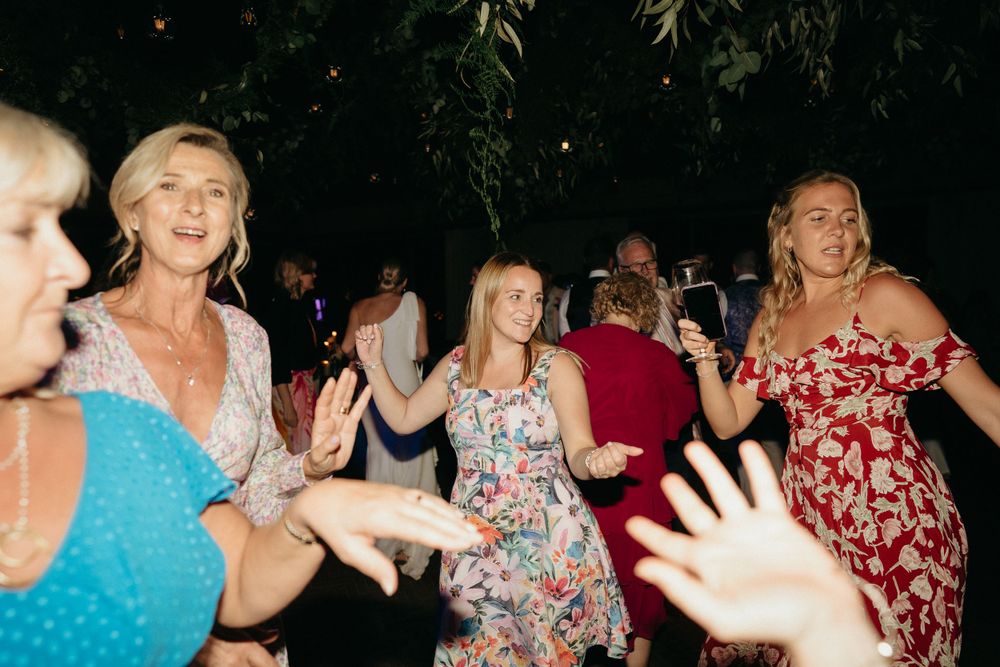 Wedding guests dance and celebrate on a festive dance floor with party lights.
