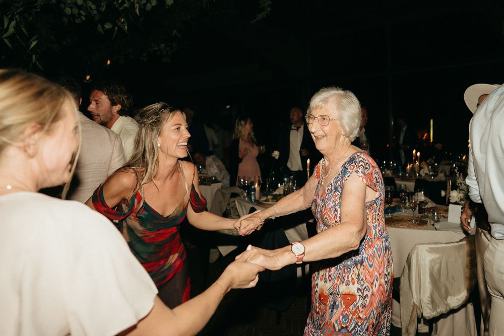 Wedding guests dancing joyfully during evening reception celebration.