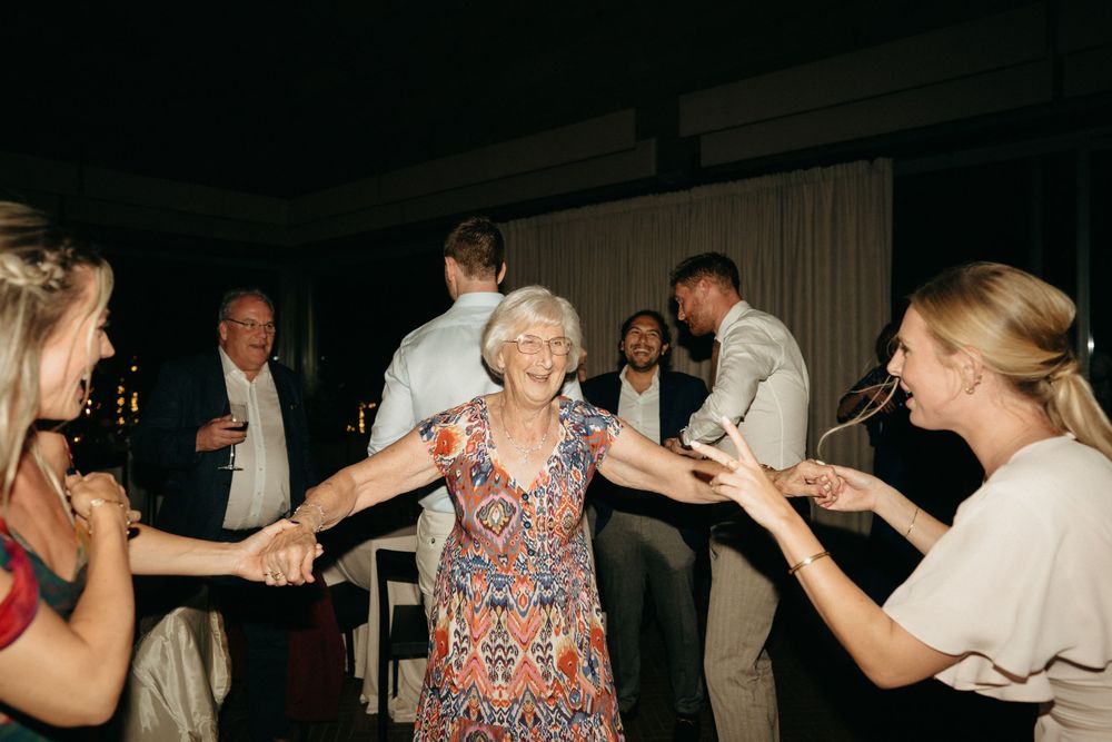Guests dance together during a lively indoor wedding reception celebration.