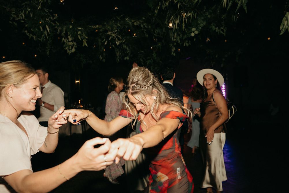 Wedding guests dancing and celebrating at nighttime outdoor reception.