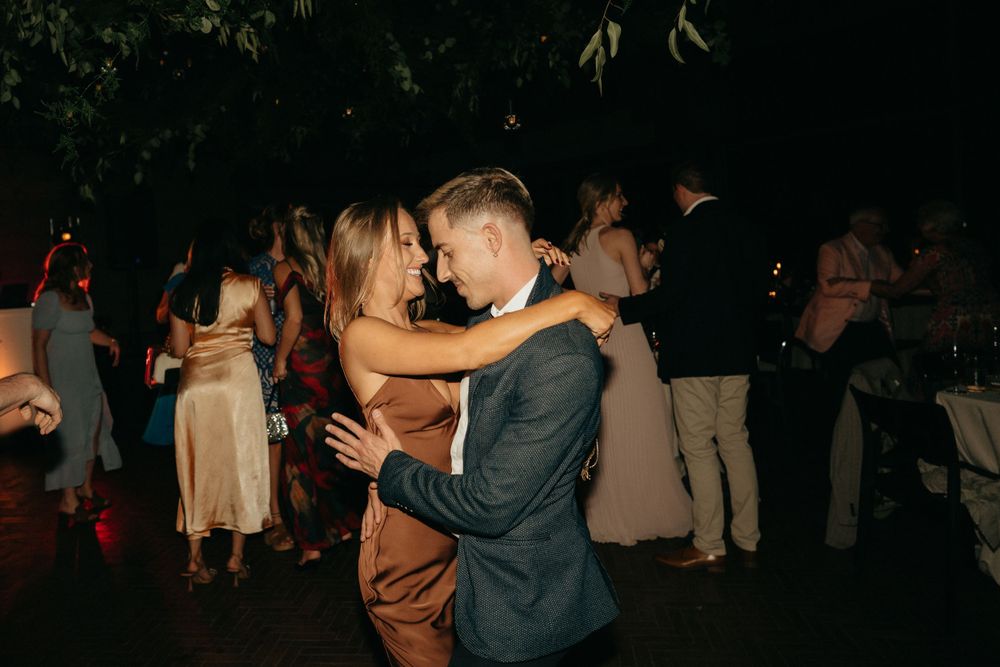 Intimate dance moment between couple at nighttime outdoor reception.