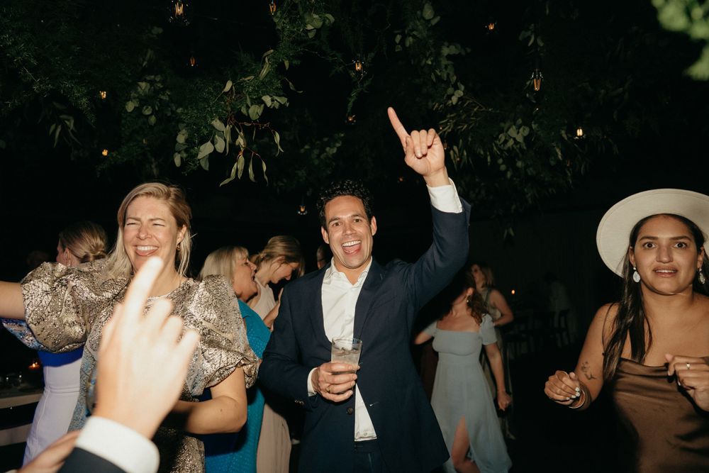 Party guests dance enthusiastically outdoors at night during a celebration event.