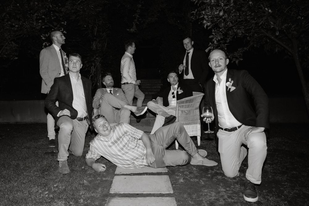 Black and white photo of groomsmen striking fun poses at a wedding celebration.