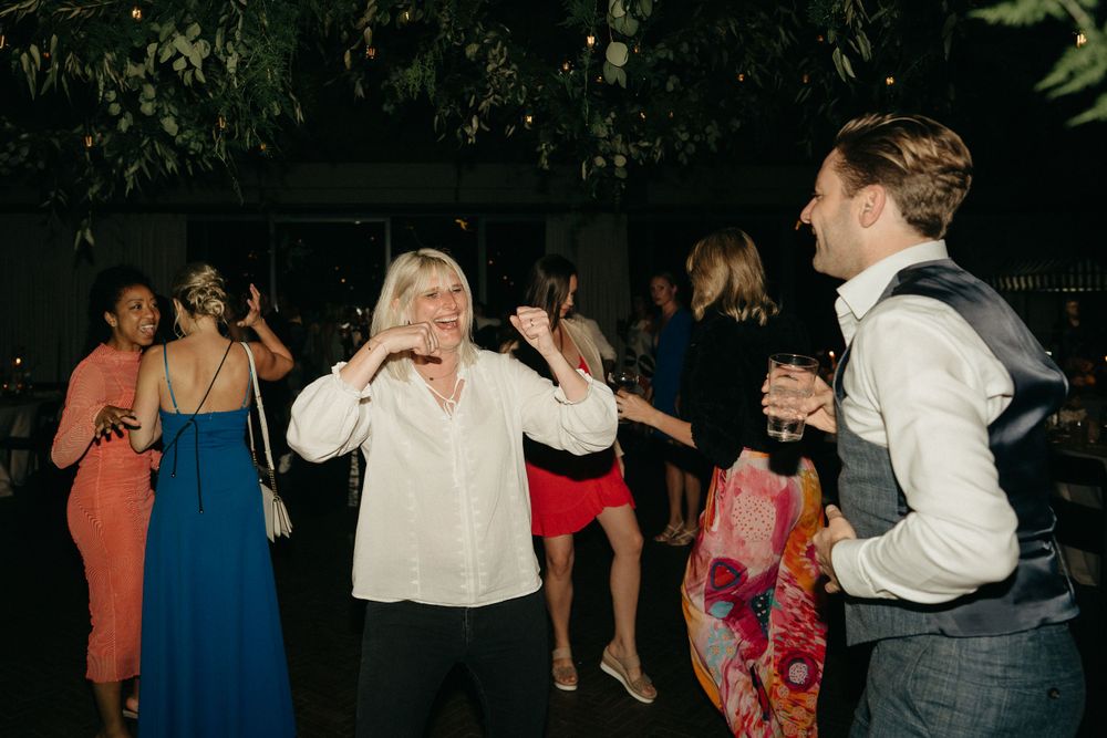 Wedding guests dancing and celebrating at a dimly lit indoor reception.