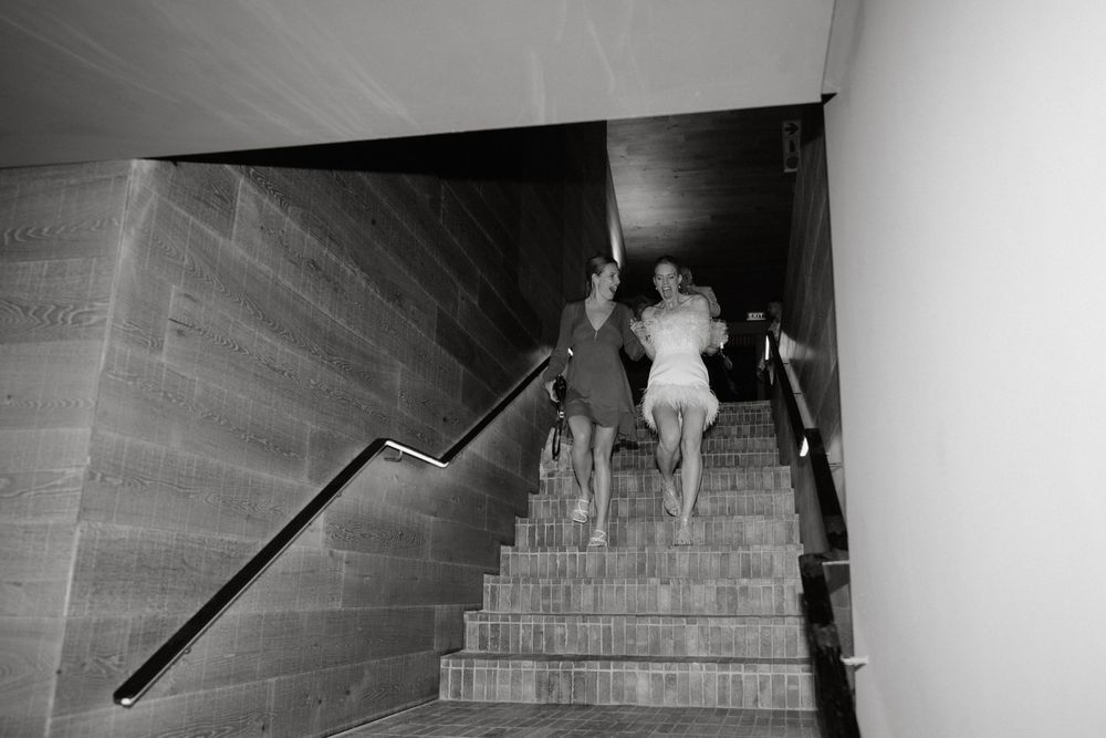 Artistic black and white shot of couple descending staircase at wedding venue.