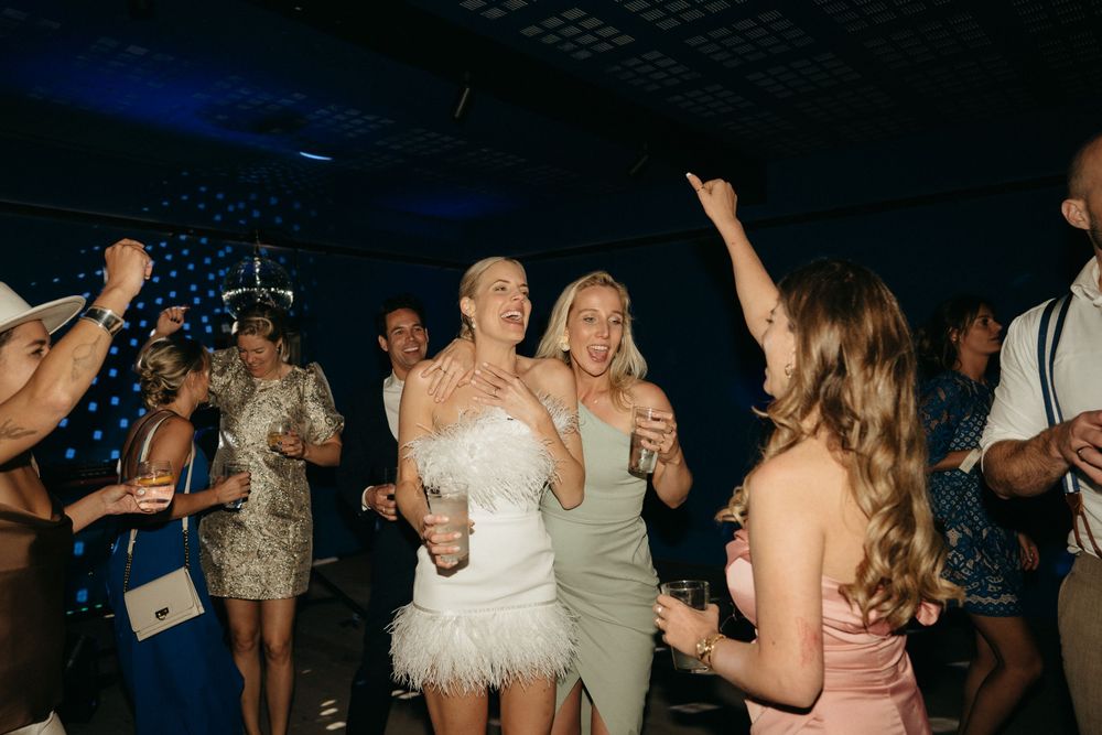 Wedding celebration on a dark dance floor with party lights and energetic dancing.