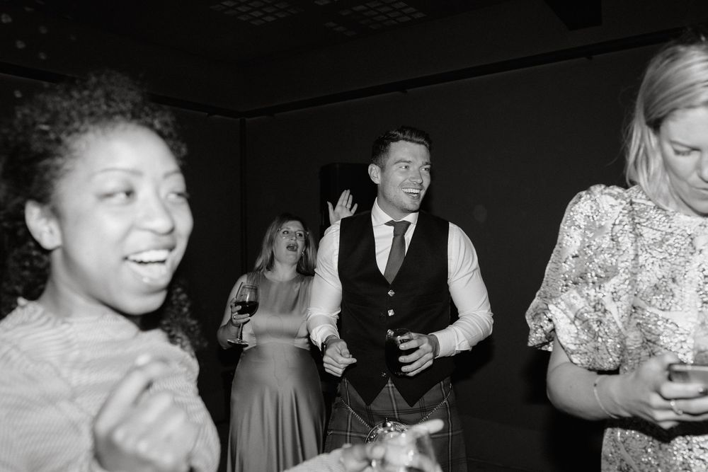 Wedding guests dancing and celebrating at reception in black and white photography.