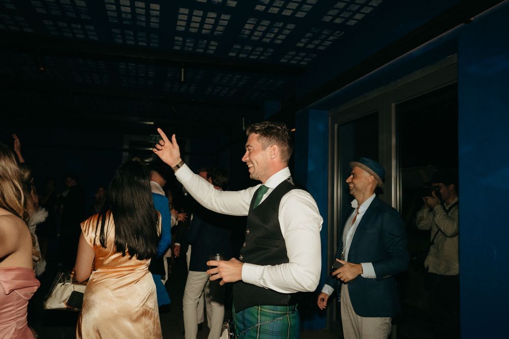 Dancing and celebration at nighttime wedding reception with guests enjoying the festivities.