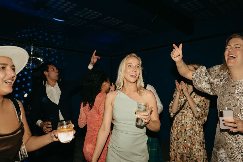 Party guests dancing and celebrating at a nighttime event with drinks in hand.
