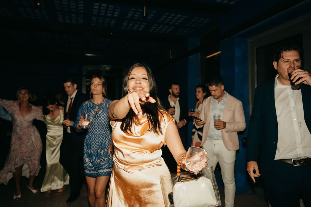 Wedding guests dancing and celebrating at a reception with people in formal attire enjoying the party atmosphere.
