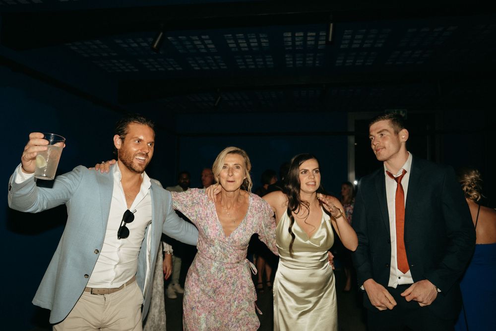 Energetic dance floor scene at wedding reception with disco lighting and party atmosphere.