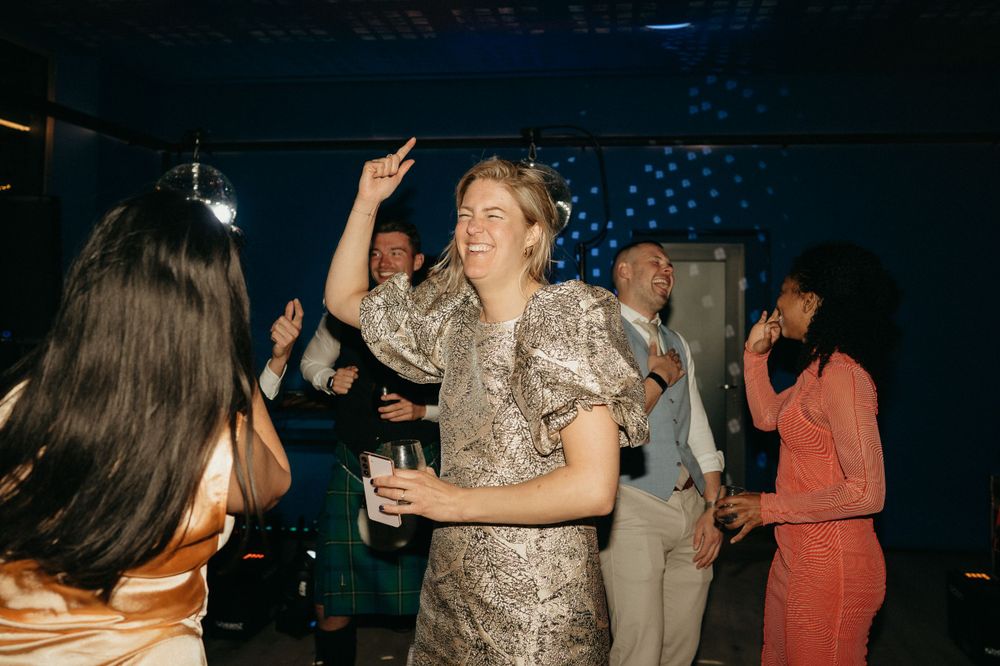 Lively dance party scene with guests in formal attire under ambient lighting.