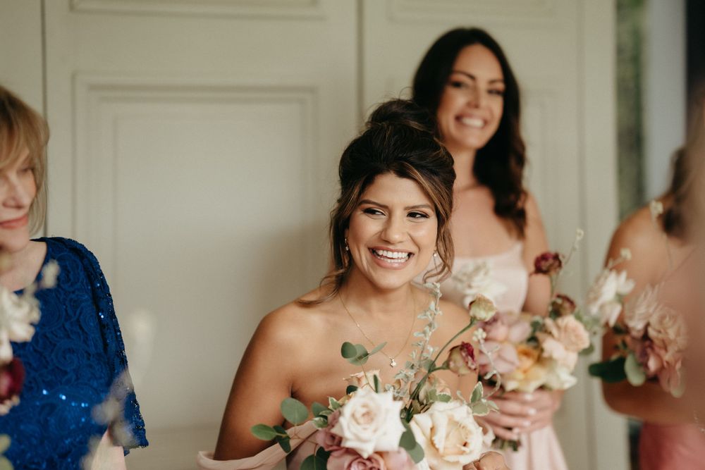 Wedding party members share joyful moments with flowers during pre-ceremony preparations.