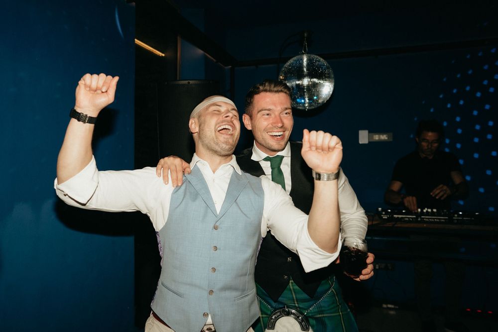 Two guests celebrating enthusiastically on dance floor under disco ball.