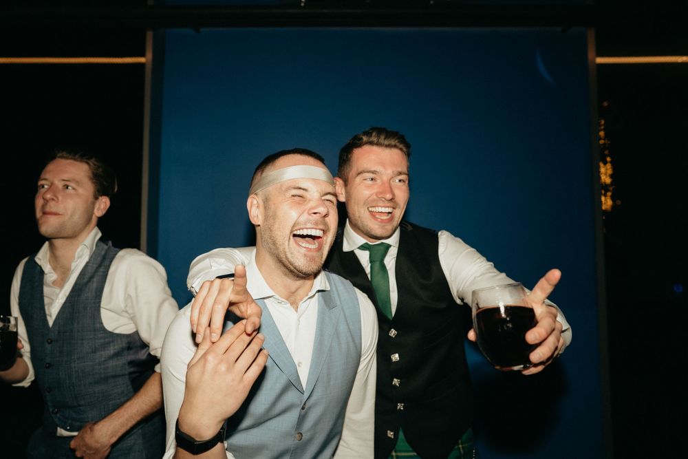 Wedding guests laughing and celebrating against a dark blue backdrop.