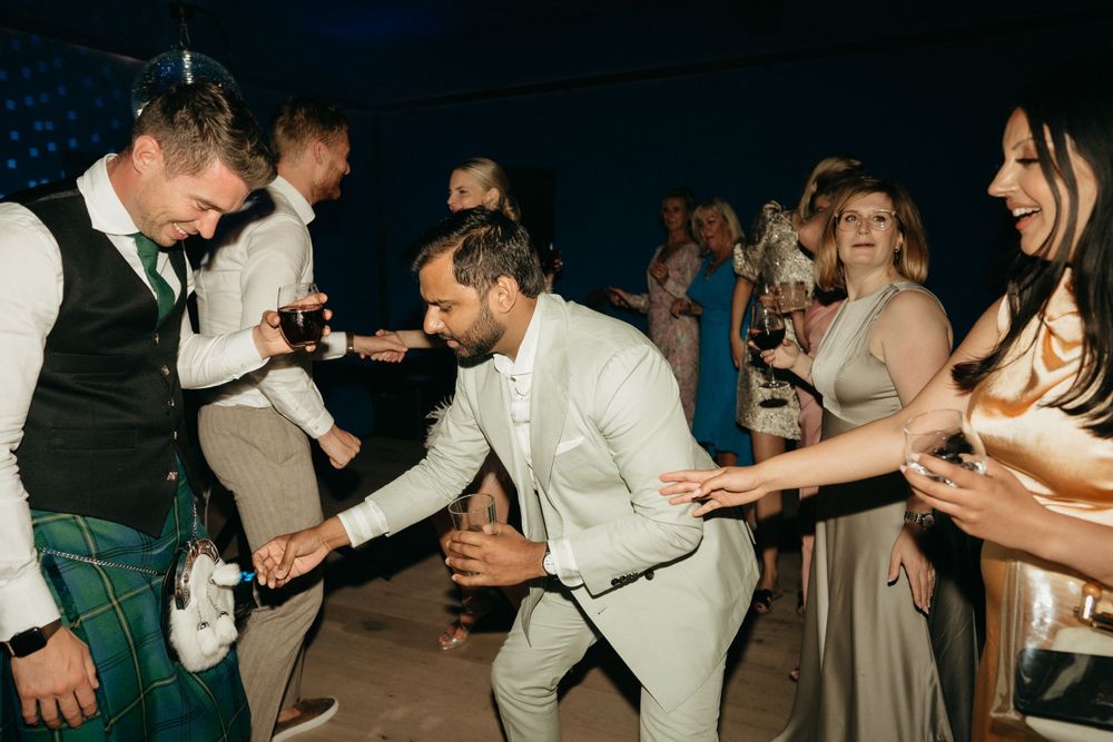 Wedding party dancing enthusiastically at nighttime reception celebration.