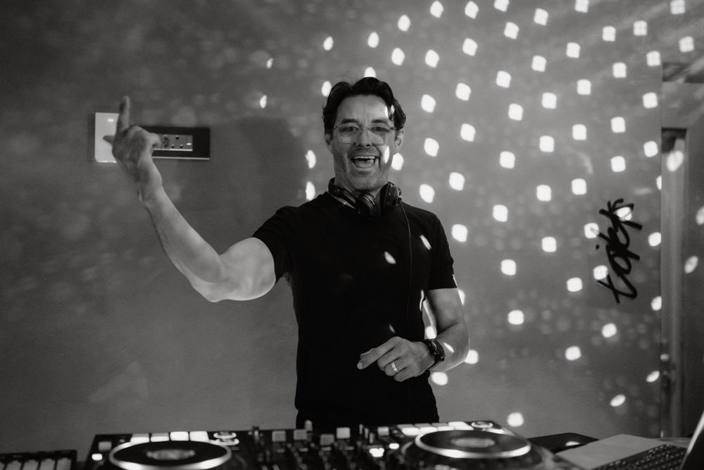 DJ performing at a wedding reception with a backdrop of glowing string lights creating a vibrant atmosphere.