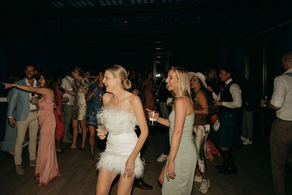 Wedding reception dance floor filled with guests in elegant attire.