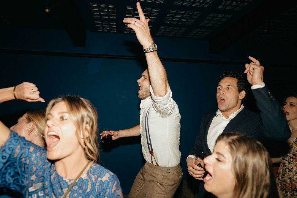 Party guests dance joyfully with raised arms in a lively celebration.