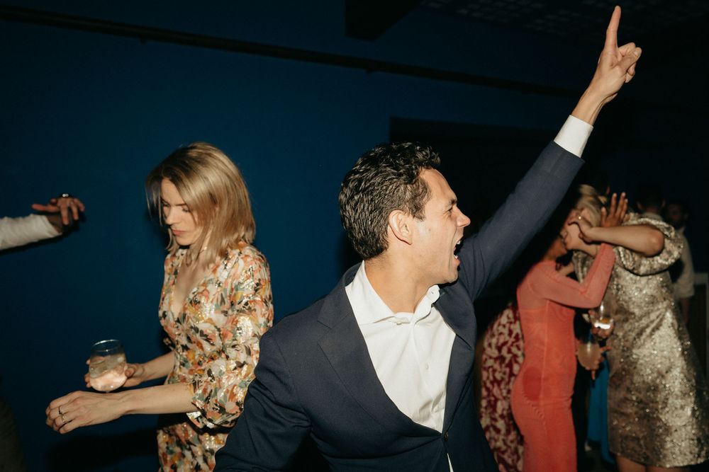 Energetic dance party scene at wedding reception with guests in motion.