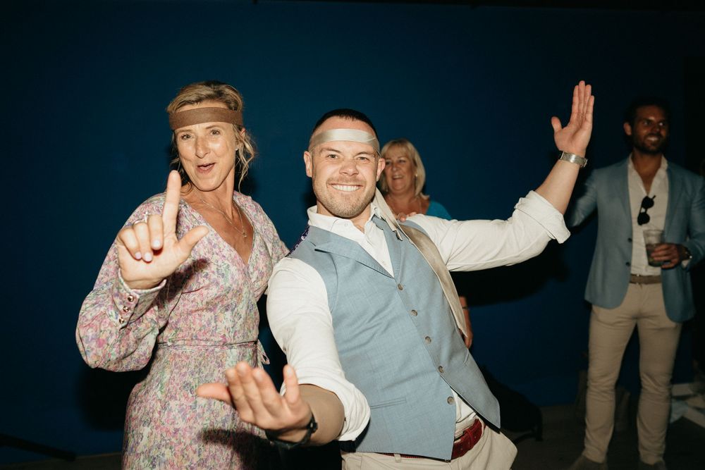 People dance enthusiastically at a nighttime wedding celebration.