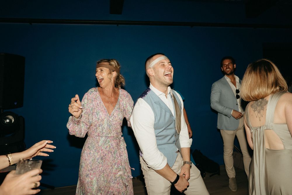 Wedding guests dancing and celebrating on the reception dance floor.