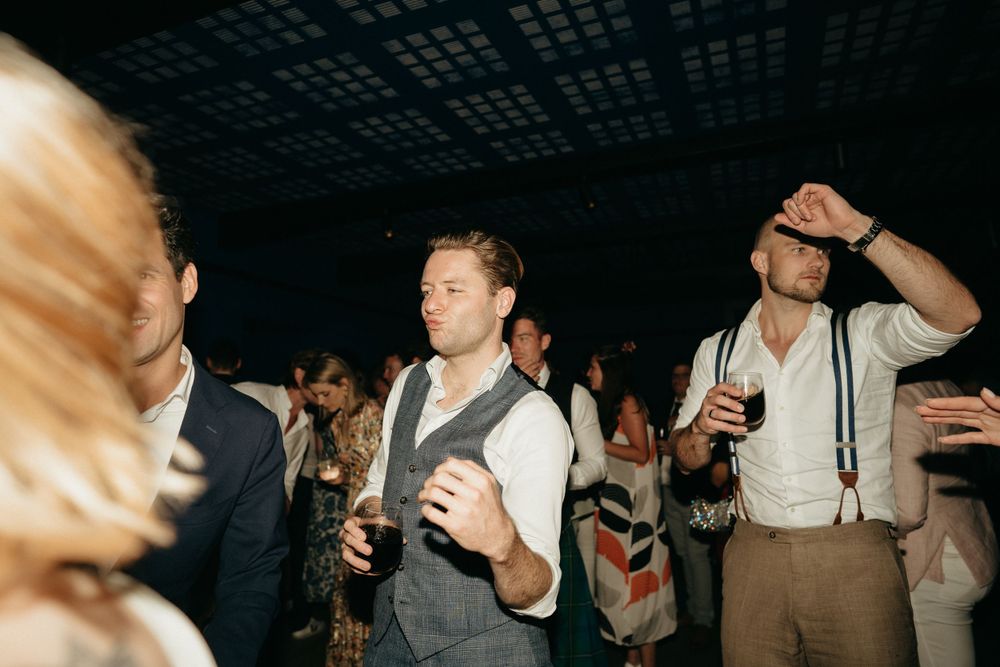 Party guests in vests and suspenders dancing at a reception.