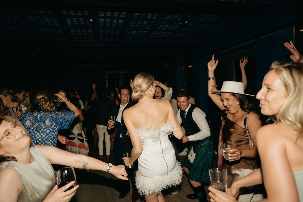 Guests dancing and celebrating on a dimly lit dance floor at an evening wedding reception.