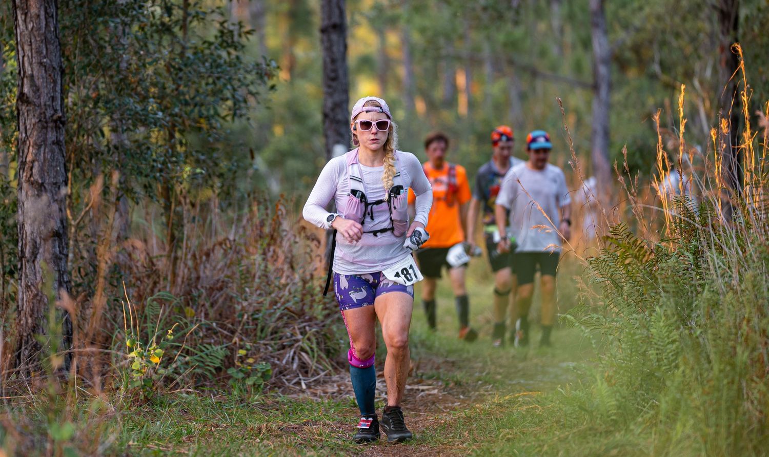 Trail runners making their way through wooded path during race.