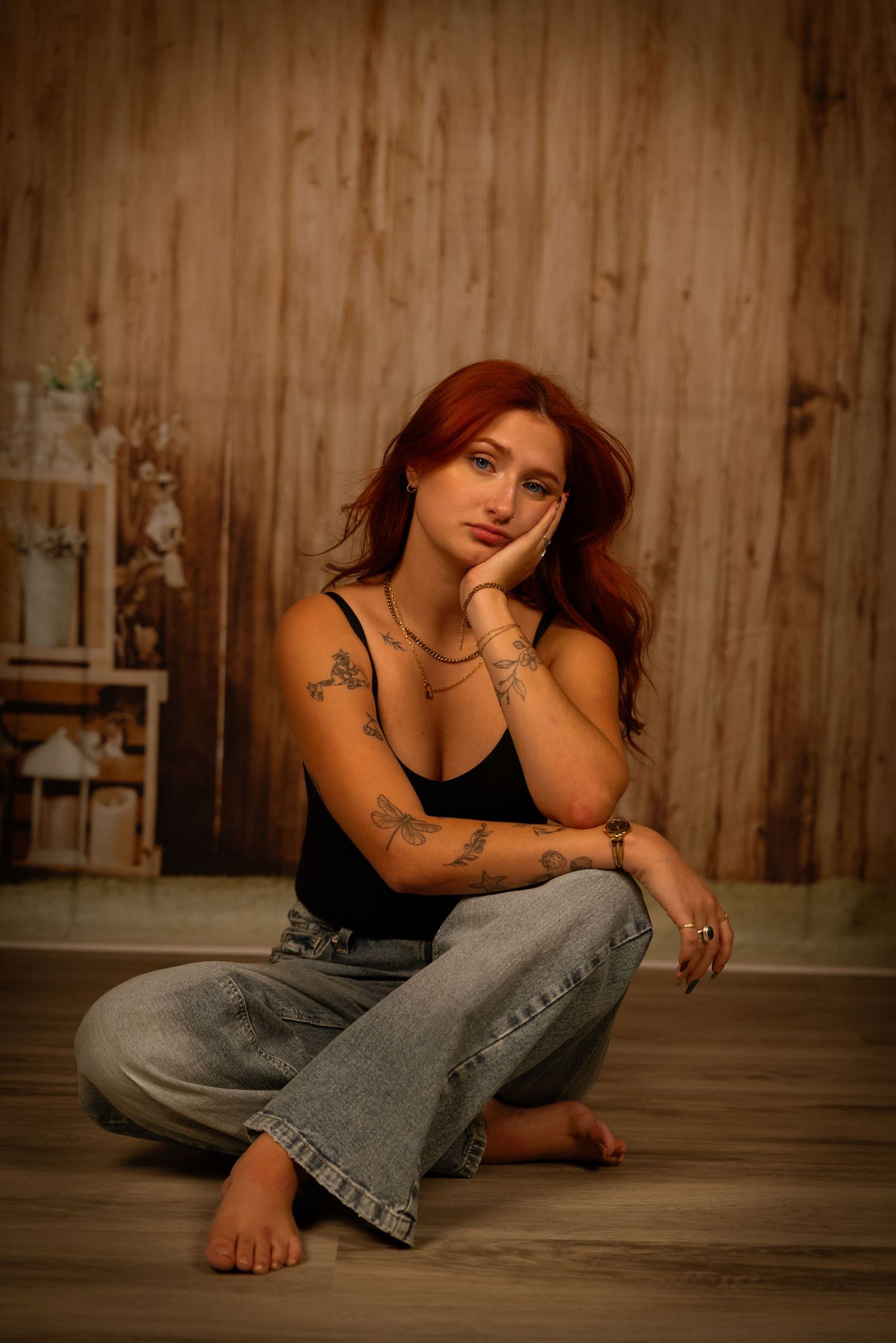 Moody portrait series of person in jeans sitting on wooden floor in atmospheric lighting with rustic backdrop.