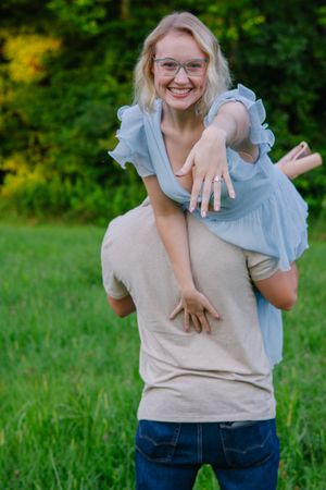 Candid shots of a couple celebrating their engagement in a green summer field.
