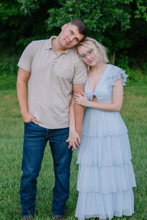 A tender moment between a couple wearing casual attire standing in a green field.