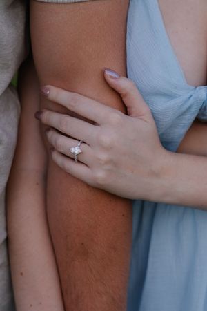 Close-up of hands embracing with an engagement ring visible on the woman's finger.