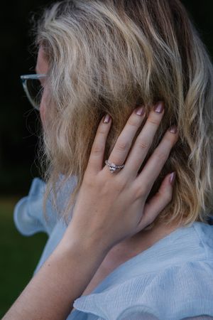 Close-up view of a woman's hand with an engagement ring running through blonde hair.