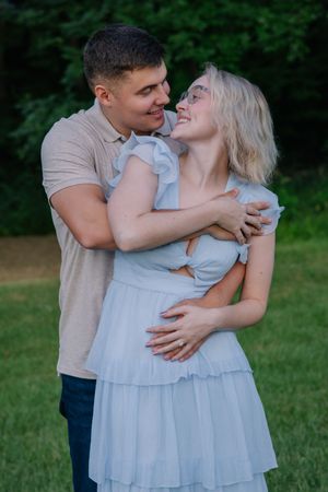 A romantic couple shares an intimate moment in an outdoor setting with green foliage.