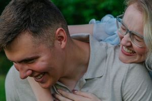 A romantic couple shares tender moments in a grassy field wearing light colored clothing.