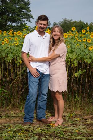 A romantic photoshoot in front of a sunflower field with a couple in casual summer outfits.