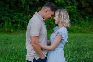 Couple shares intimate moments in a natural outdoor setting with green vegetation.