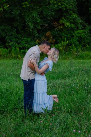 Couple in light colored clothing sharing romantic moments in tall grass.