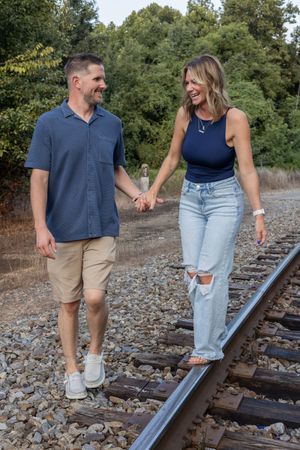 Candid shots of two people walking and laughing together on train tracks.