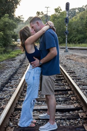 Couple sharing an intimate moment on railroad tracks during a photo session at sunset.
