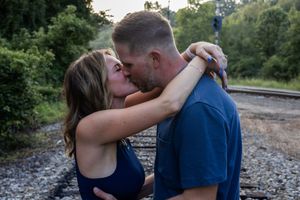 Romantic couple embracing on train tracks during an outdoor photoshoot.