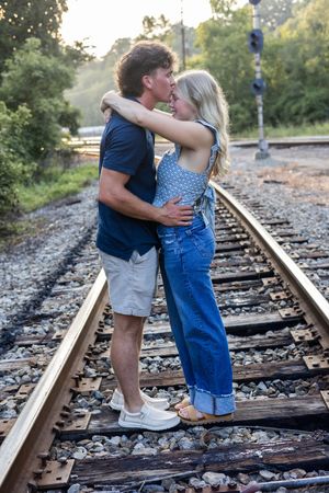Sweet moments captured between couple during sunset photoshoot on train tracks.