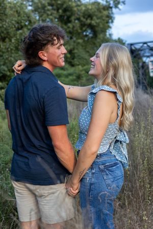 A joyful couple shares a laugh while holding hands during their outdoor photoshoot.