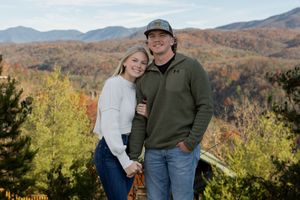 Couple shares intimate moment against backdrop of colorful autumn mountains.