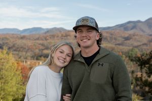 Couple smiles together on mountain overlook during fall season.