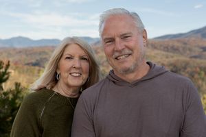Couple embraces while enjoying mountain vista with fall colors.